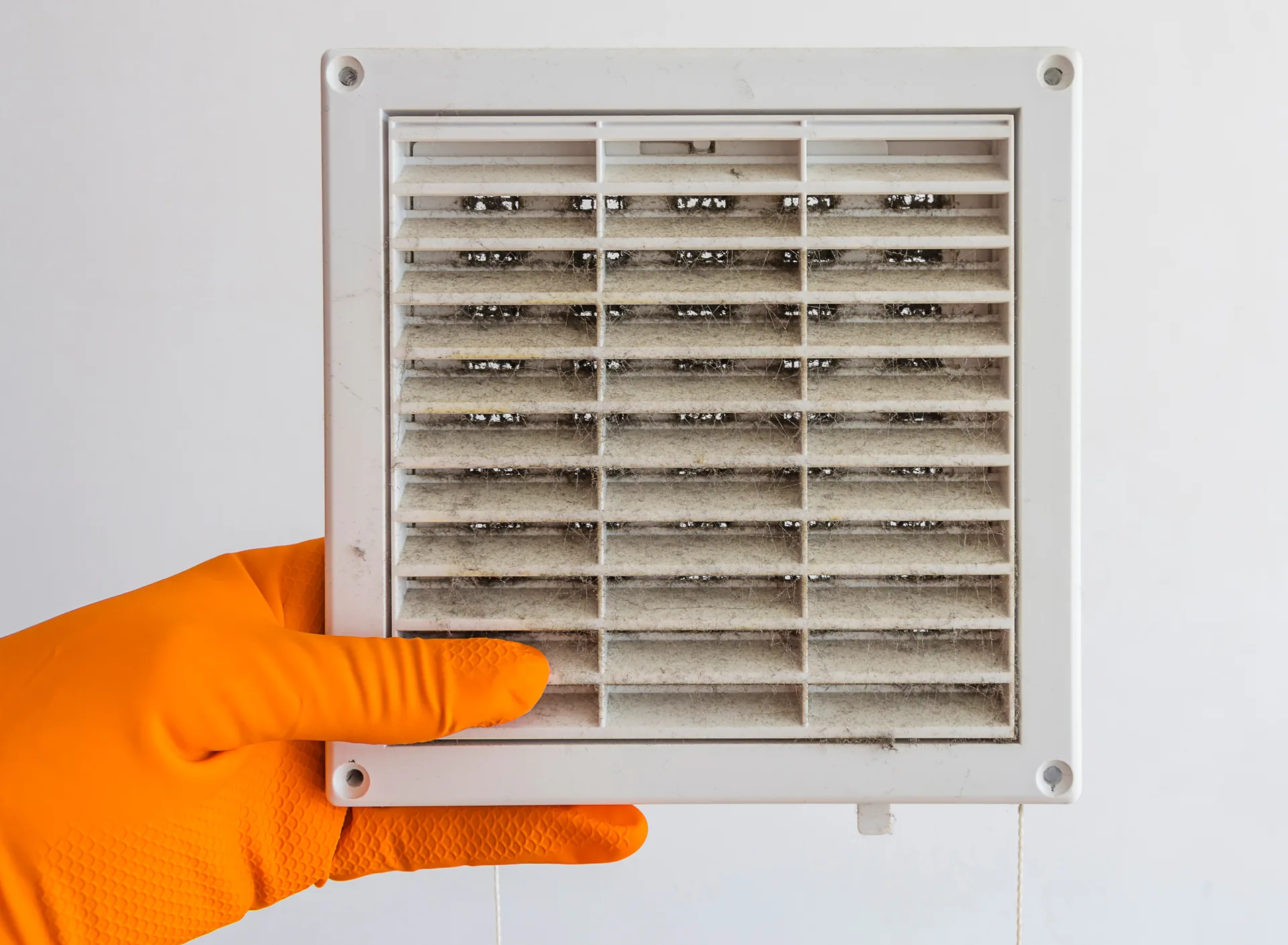 Gloved hand holding a dusty air vent cover, showing poor indoor air quality in an Avondale, AZ home